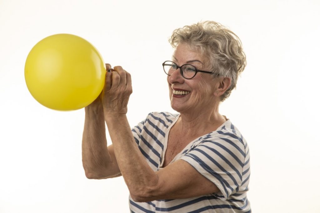 Ältere Frau mit gelben Luftballon